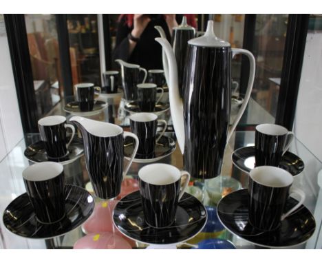 A Cmielow coffee service, with six tea cups and saucers, jug and coffee pot, the 1950's elongated design with black ground
