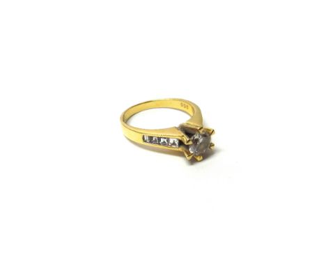 A gold and diamond set ring, claw set with the principal circular cut diamond at the centre, between emerald cut diamond set 