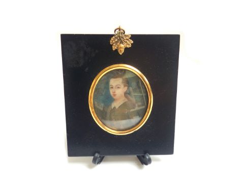An early 18th century portrait miniature on ivory depicting a young boy in period dress, in a gilt metal and ebonised frame, 