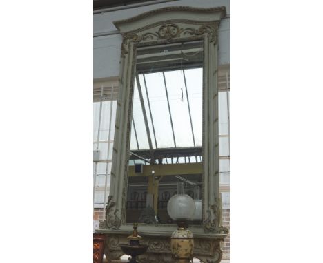 A large parcel gilt grey painted wall mirror, with opposing 'C' scroll frieze, over rectangular plate and serpentine lower sh