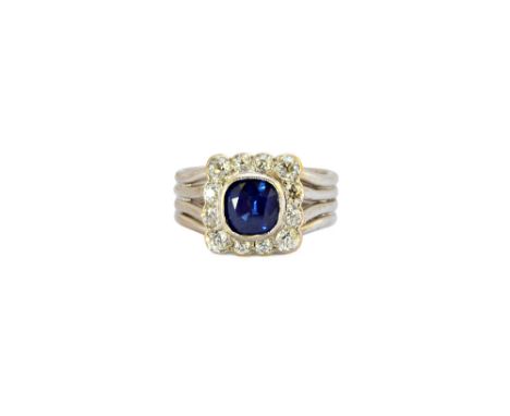 A sapphire and diamond set cluster ring, mounted with the cushion shaped sapphire at the centre, in a surround of twelve cush