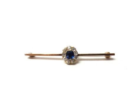 A gold, sapphire and diamond set cluster bar brooch, claw set with the cushion shaped sapphire at the centre, within a surrou