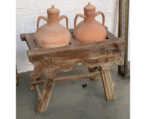 A pair of 20th century terracotta oil jars, in a trestle style stand with carved floral motif, each jar approx. 48cmH 