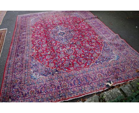 A large Persian carpet,&nbsp;having central floral medallion on a red and blue ground, 400 x 298cm. 
