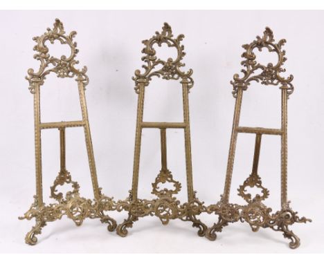 A set of three Victorian style gilt brass easel stands with scroll and acanthus frames, 53cm.