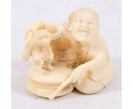 Japanese carved ivory netsuke of a seated drummer and a dancing monkey pulling his ear. 5.5cm, Meiji.