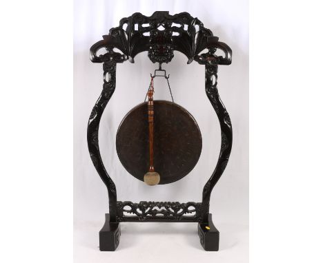 Chinese hardwood gong stand and bronze circular gong and beater, the stand carved and pierced with lion dog, peaches and foli