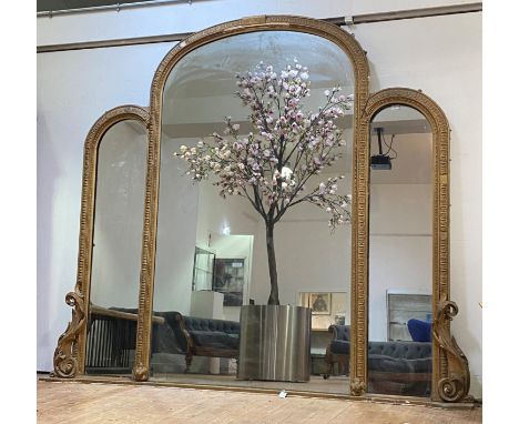 An impressive gilt composition and gesso framed three sectional overmantel mirror, 19th century, the central arched panel wit
