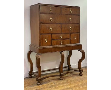 A 1920's walnut chest on stand of George I design, the top with moulded edge above a combination of nine drawers with herring