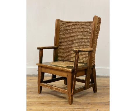 A Scottish pine child's Orkney chair, circa 1920's, the woven rush back and cord seat flanked by open arms with carved termin