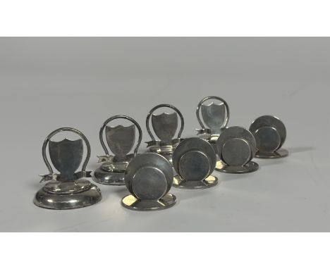 Two sets of four silver menu card holders, early 20th century: the first of two graduated discs on a circular base, Sampson M
