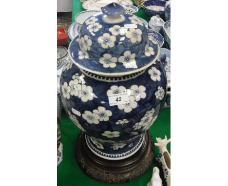 A 19th Century Chinese blue and white prunus blossom decorated baluster shaped vase and cover on a well carved hardwood stand