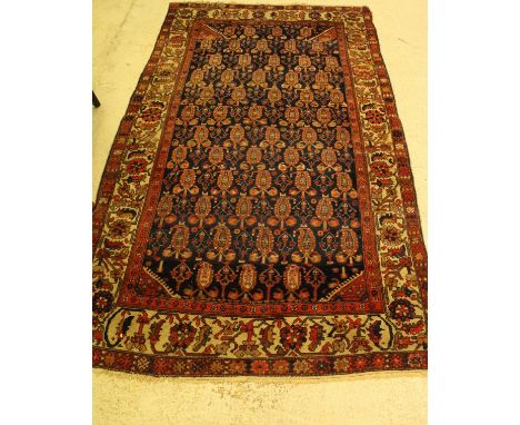 A Persian carpet, the central panel set with repeating hook motifs on a dark blue ground, within a stepped red, cream and blu