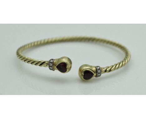 An 18 carat gold torque style bangle set with love heart shaped rubies and diamonds to the ends, approx total weight 16.2 g