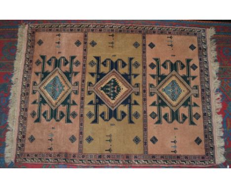 A mid 20th century carpet, the peach ground segmented into three panels centered by stylised animals and foliage encased with