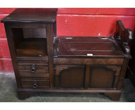 An oak Priory style telephone table, hinged seat, carved lion handrail, 90cm wide