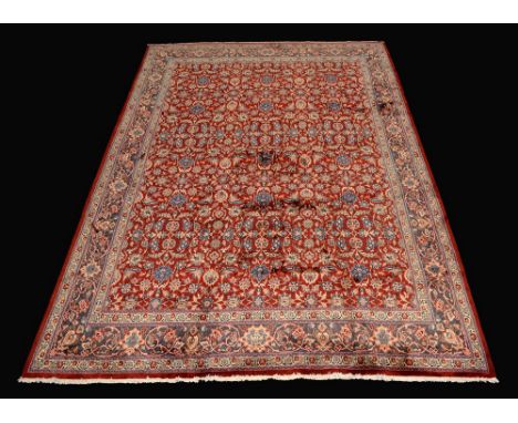 A Kirman carpet, the crimson ground bordered by a cerulean ground with flowers and foliage in tones of ecru and blue, 410cm x