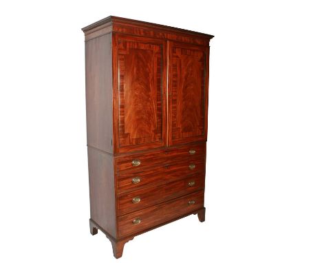 A late George III mahogany tray wardrobe or press, c.1820, the dentil cornice above two figured mahogany doors opening to rev