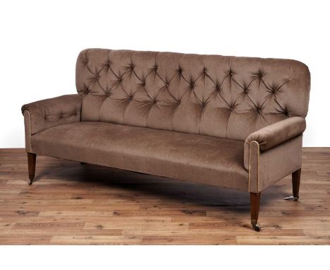 An early 20th Century button back sofa, with scroll over arms and stuffover seat pad, raised on four square tapered mahogany 