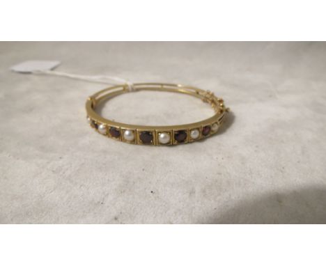 An Edwardian yellow gold hinged bangle set with garnets and pearls, 13.9 grams