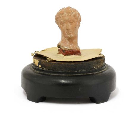 A Greek terracotta head of Apollo, 1st century, 6cm high, on a turned wooden base under a glass dome, 27cm high overallProven
