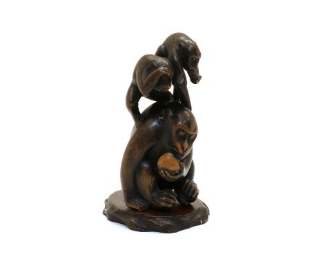 A Japanese wood carving, 20th century, of a seated monkey holding a peach in his left hand, two smaller monkeys on its back, 
