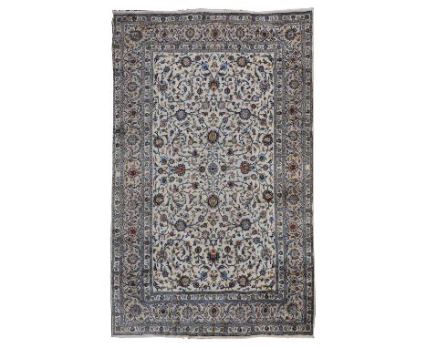 A Persian Kashan carpet, 20th century, woven with scrolling floral and foliate decoration, on a cream and blue ground, 390 x 