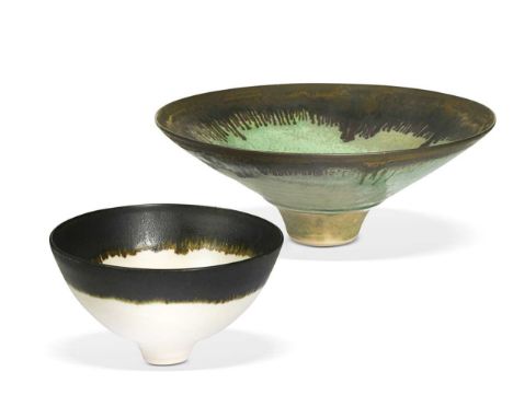 In the manner of Lucie Rie, two unsigned studio pottery footed bowls, the larger with everted manganese rim under volcanic gr