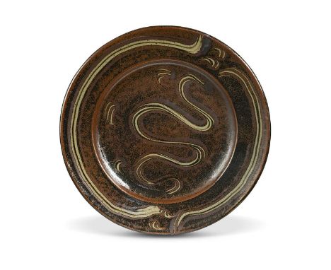 § Ray Finch (1914-2012) for Winchcombe Pottery, a stoneware charger, in tenmoku breaking to kaki glaze with meander decoratio
