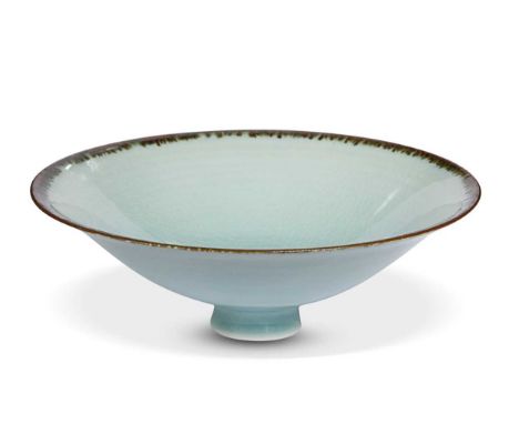 In the manner of Dame Lucie Rie, a footed porcelain bowl, in pale celadon crackle glaze and with manganese rim19cm diameter