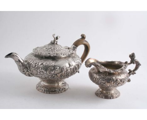 A GEORGE IV EMBOSSED TEA POT & MATCHING MILK JUG with squat circular bodies, pierced rims & cartouches with applied putti, th