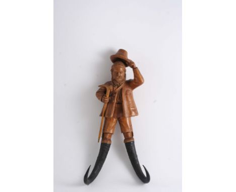 A BLACK FOREST CARVED WOODEN NOVELTY COAT HOOK in the form of a gentleman in breeches, doffing his hat & clutching a walking 