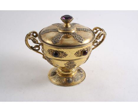 A SCOTTISH SILVERGILT "CELTIC" CUP & COVER with applied strapwork, chased reserves & domed bosses, bird mask & scroll handles