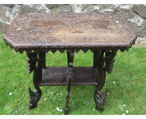 A carved oak occasional table, the top decorated with fielded panel of elephants and large raised on six stylized carved legs