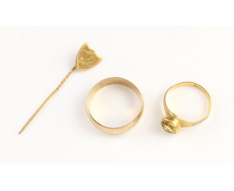 Two rings and a stick pin, including a round cut yellow sapphire ring, set in a rub over setting, in 22 ct yellow gold, size 