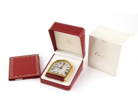 Cartier, A  travelling alarm clock the gold plated case containing an arched signed dial with Roman numeral hour markers, fit