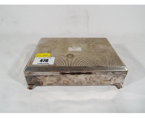 A silver plated cigar / cigarette box, engine turned decoration supported on four feet, 5cm x 17cm x 12cm