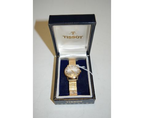 A gents Tissot 9ct gold cased wrist watch having champagne dial with Arabic and baton markers on flexible link strap in fitte