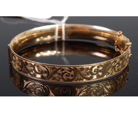 A rolled gold hinge bangle with safety chain   Condition Report / Extra Information  Diameter 7.9cm.