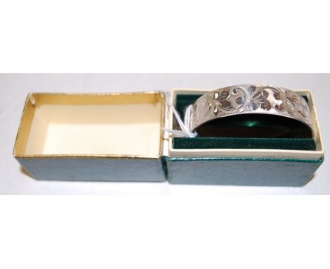 A 1970s silver bangle having a floral engraved decoration and presentation inscription in fitted green leather case Condition