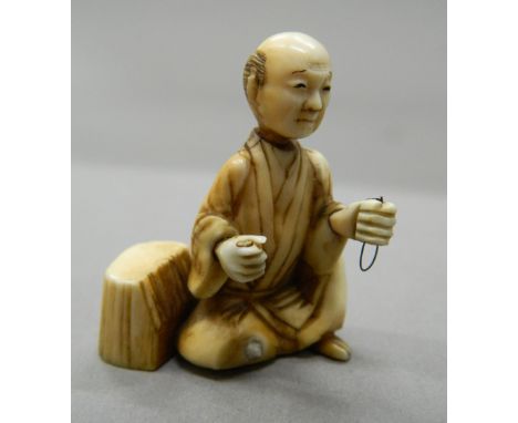 A 19th century ivory netsuke of a man seated beside a tree stump.  4.25 cm high.