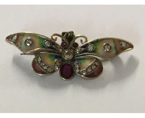 A pendant in the form of a butterfly the wings with coloured enamel inset with diamonds and rubies.