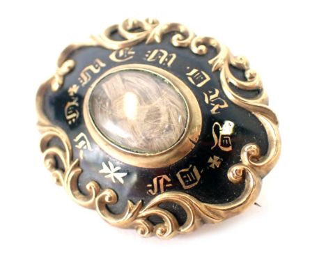A Victorian memorial brooch, with black enamel front and central locket, inscribed in memory of, in a yellow metal casing wit
