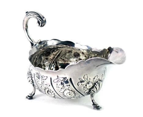 A Victorian silver sauce boat, with a fluted border acanthus leaf handle, embossed floral decoration with shield bearing the 