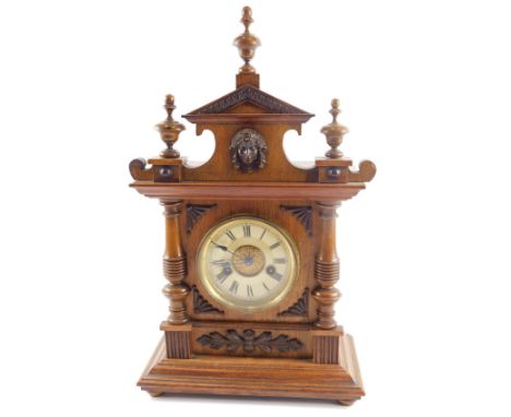 A late 19thC walnut cased mantel clock, with arched top with applied crest, on a white enamel dial with blue hands and thirty