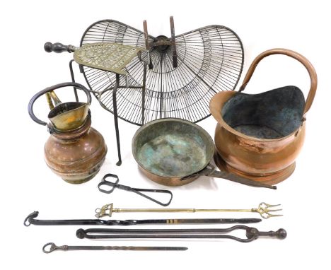 A group of copper and brass wares, comprising a peacock fan fire guard, trivet, ram head poker, copper coal scuttle, saucepan