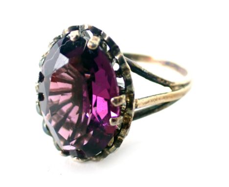 An amethyst dress ring, set with oval amethyst in four double claw setting with petalated border on a raised basket, yellow m