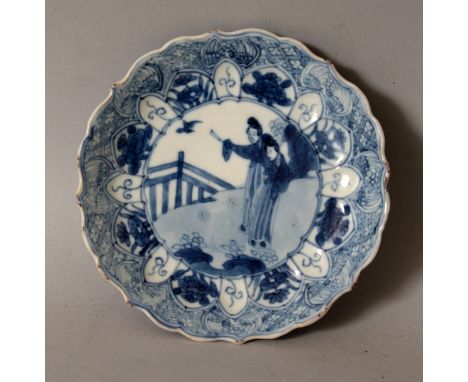 A CHINESE KANGXI PERIOD BLUE & WHITE PORCELAIN SAUCER, circa 1700, with a barbed-edge rim, painted to its centre with a scene