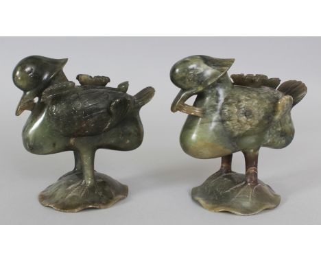 A PAIR OF 19TH/20TH CENTURY CHINESE JADE-LIKE GREEN SOAPSTONE MODELS OF MANDARIN DUCKS, each standing on a lotus leaf and bea