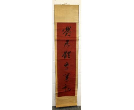 A CHINESE HANGING SCROLL, decorated with calligraphy in black reserved on a red ground, the picture itself approx. 55in x 13.